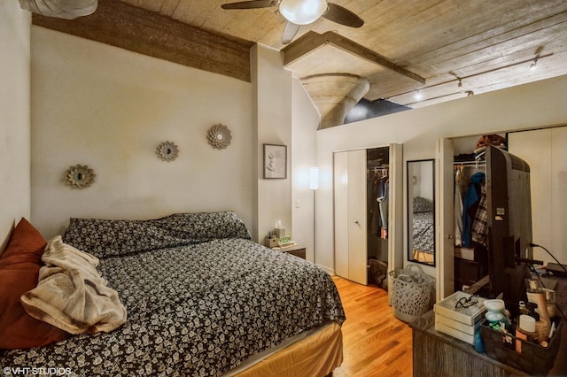 bedroom with wooden ceiling, ceiling fan, wood finished floors, beamed ceiling, and multiple closets