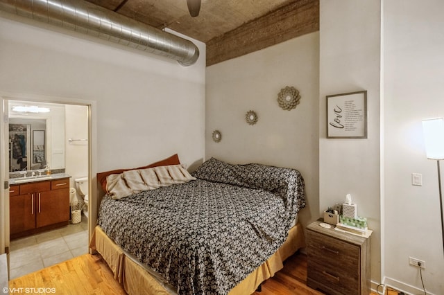 bedroom featuring light wood-style floors, connected bathroom, and a sink