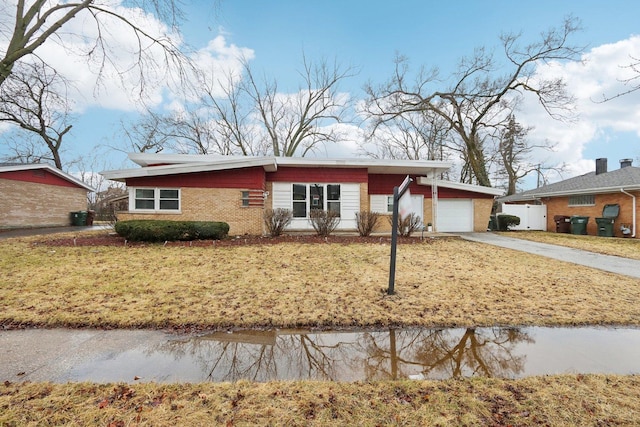 mid-century home featuring a garage, a front yard, brick siding, and driveway