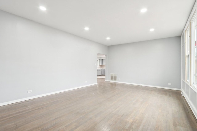 empty room featuring baseboards, visible vents, wood finished floors, and recessed lighting