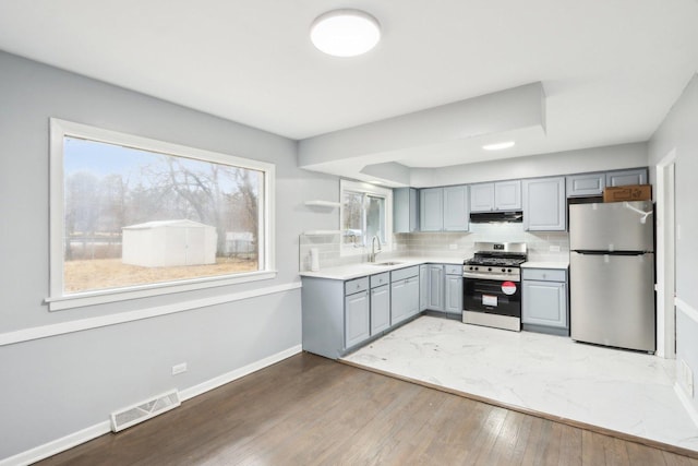 kitchen with visible vents, decorative backsplash, stainless steel appliances, gray cabinetry, and a sink