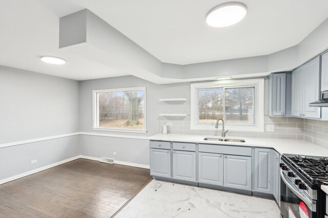 kitchen with stainless steel gas range oven, gray cabinets, and a sink