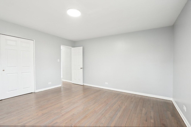 unfurnished bedroom with a closet, baseboards, and wood finished floors