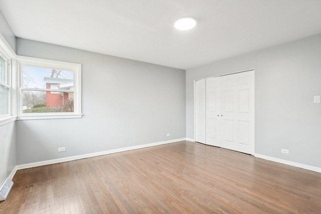 unfurnished bedroom featuring a closet, visible vents, baseboards, and wood finished floors