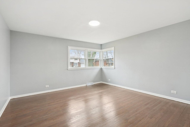 spare room with dark wood-type flooring and baseboards