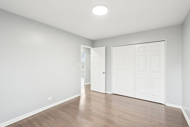 unfurnished bedroom with a closet, baseboards, and wood finished floors