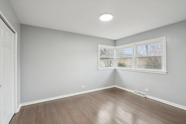 unfurnished bedroom with dark wood-style flooring, visible vents, and baseboards