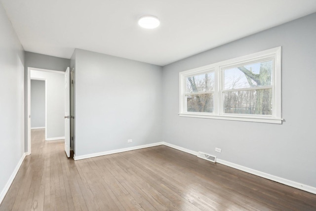 unfurnished room featuring visible vents, baseboards, and wood finished floors