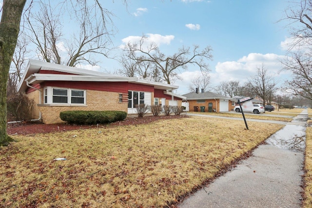 view of front of home with driveway, a front yard, and brick siding