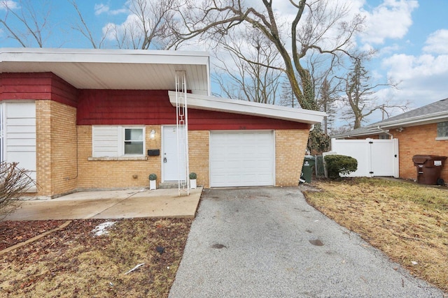 exterior space featuring a garage, driveway, brick siding, and fence