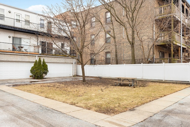 view of yard featuring driveway, an attached garage, and fence