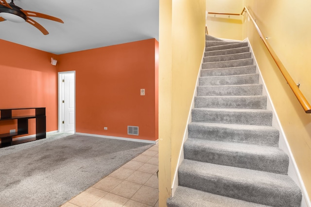 stairway featuring carpet, visible vents, ceiling fan, and tile patterned floors