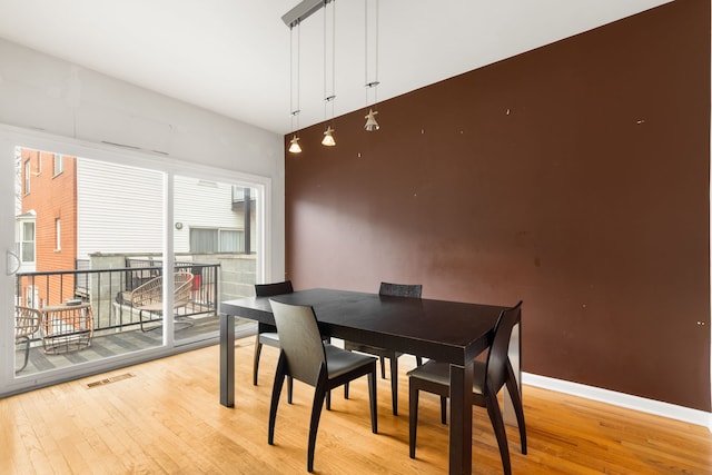 dining space with light wood-type flooring, visible vents, and baseboards