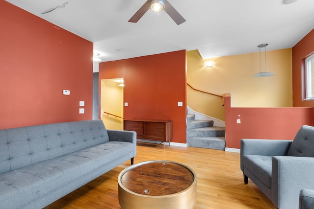 living area with stairs, ceiling fan, baseboards, and wood finished floors