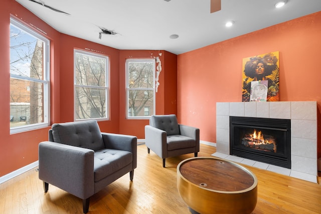 sitting room with a tiled fireplace, baseboards, wood finished floors, and recessed lighting