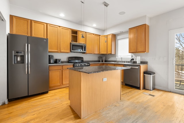 kitchen featuring light wood-style floors, a kitchen island, appliances with stainless steel finishes, and a sink