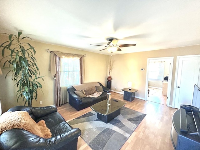 living room featuring light wood-style floors, ceiling fan, and baseboards