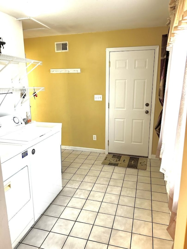 interior space with light tile patterned floors, laundry area, washing machine and dryer, and visible vents