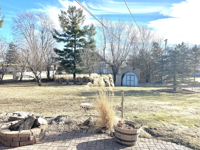 view of yard with a storage shed, a fire pit, a patio, and an outbuilding