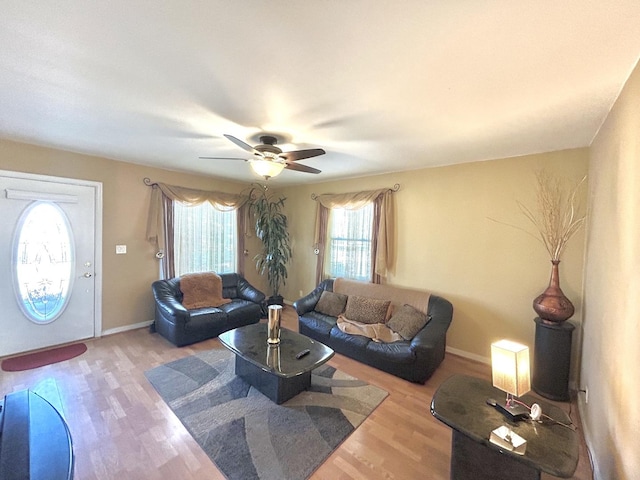 living area featuring a ceiling fan, baseboards, and wood finished floors