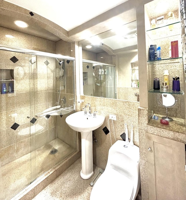 bathroom with toilet, a shower stall, and tile walls