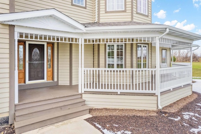 view of exterior entry featuring a shingled roof and a porch