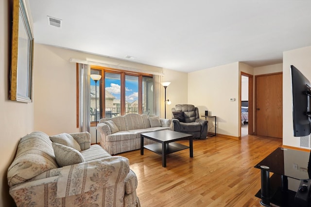 living room with light wood finished floors, visible vents, and baseboards