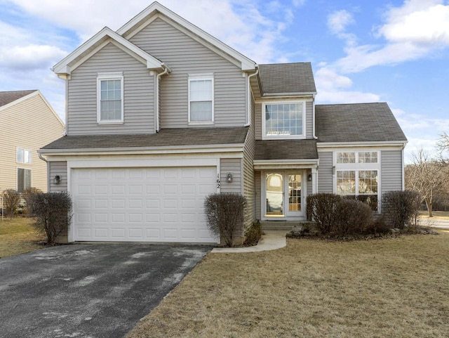 traditional home with aphalt driveway, a front yard, and an attached garage