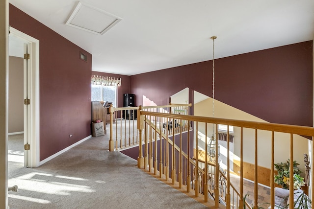 corridor with visible vents, baseboards, an upstairs landing, carpet, and attic access