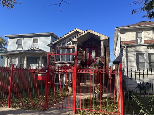 view of front of house with brick siding, a porch, a fenced front yard, and a gate