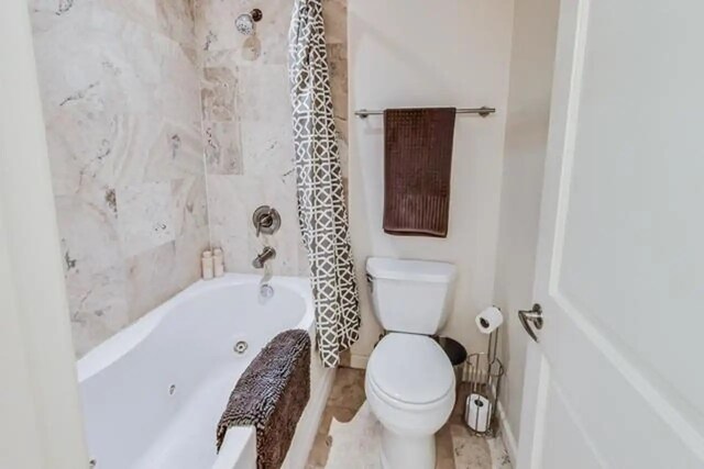 bathroom featuring toilet and a combined bath / shower with jetted tub