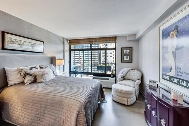 bedroom with expansive windows, concrete floors, and a wall mounted AC