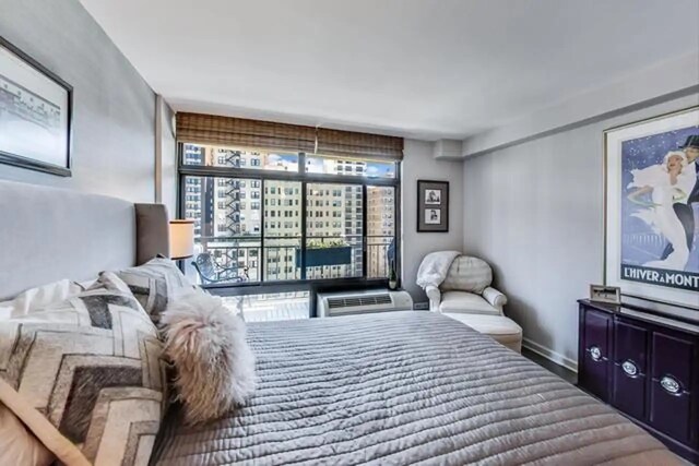 bedroom featuring a wall mounted AC and baseboards