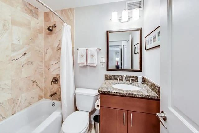bathroom featuring visible vents, toilet, vanity, and shower / tub combo