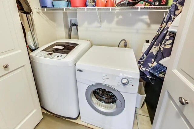washroom with light tile patterned floors, laundry area, and washer and clothes dryer