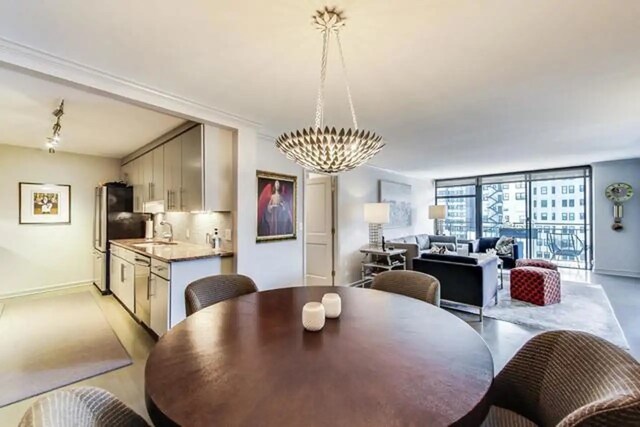 dining space featuring a wall of windows, baseboards, a notable chandelier, and finished concrete flooring