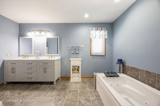 bathroom with double vanity, a whirlpool tub, baseboards, and a sink