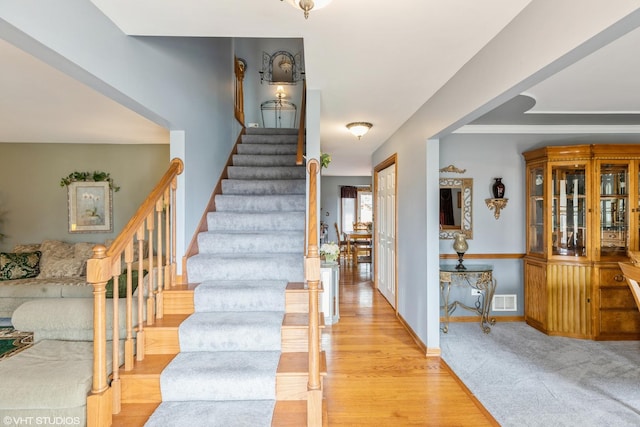 staircase with visible vents, baseboards, and wood finished floors