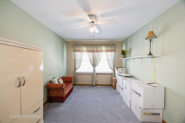 living area with light colored carpet, baseboards, and a ceiling fan