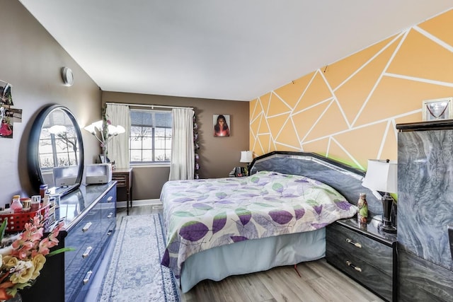 bedroom featuring an accent wall and wood finished floors