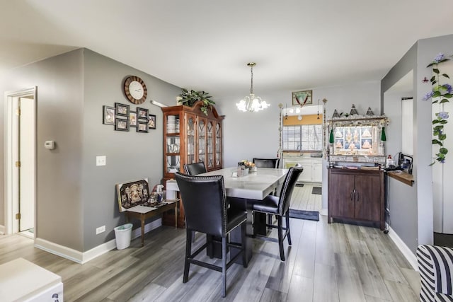 dining area featuring an inviting chandelier, light wood-style flooring, and baseboards