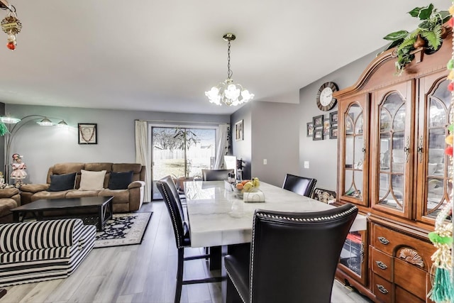 dining area with light wood-style flooring and a notable chandelier