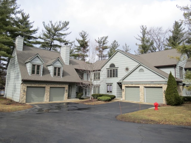 view of front of house with a garage, roof with shingles, a chimney, and driveway