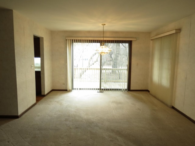 carpeted empty room with baseboards and a notable chandelier