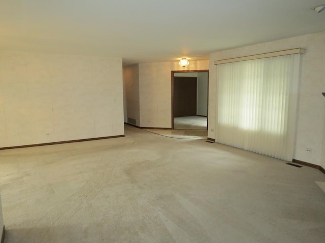 unfurnished room with baseboards, visible vents, and light colored carpet