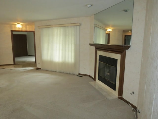 unfurnished living room featuring carpet floors, a tile fireplace, and visible vents