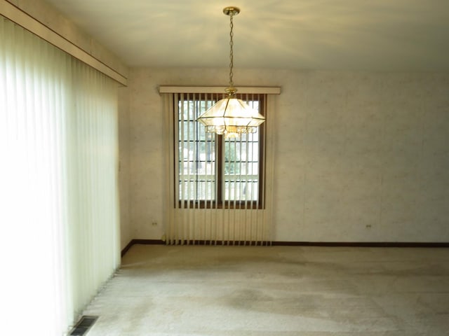 unfurnished room featuring carpet, visible vents, and a chandelier