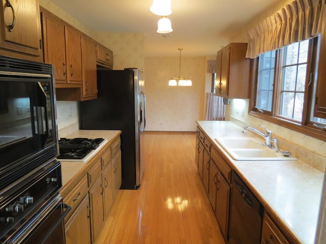 kitchen featuring black appliances, a sink, light countertops, and wallpapered walls