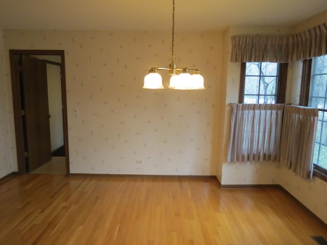 unfurnished dining area with wallpapered walls, visible vents, and wood finished floors