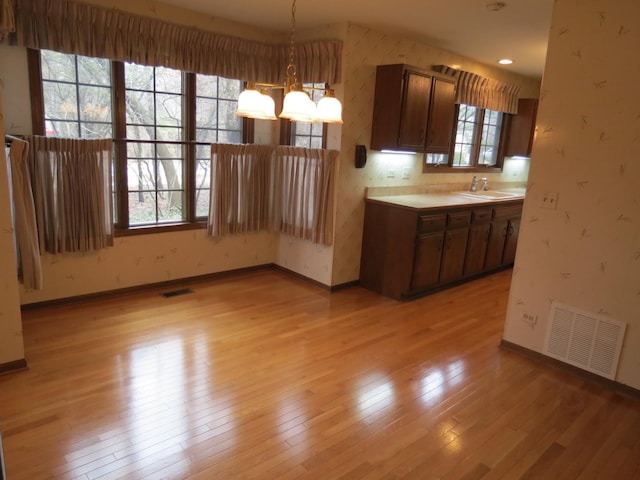 kitchen with light wood finished floors, visible vents, and wallpapered walls